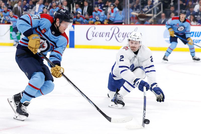 Jan 27, 2024; Winnipeg, Manitoba, CAN; Winnipeg Jets left wing Nikolaj Ehlers (27) is stick checked by Toronto Maple Leafs defenseman Simon Benoit (2) in the second period at Canada Life Centre. Mandatory Credit: James Carey Lauder-USA TODAY Sports