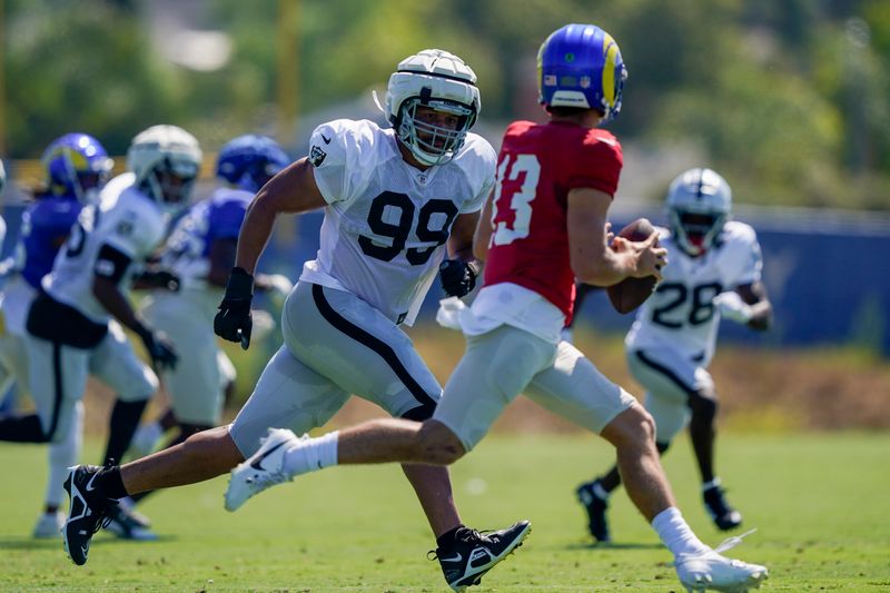 Las Vegas Raiders defensive end Jordan Willis (99) chases Los Angeles Rams quarterback Stetson Bennett (13) during a joint NFL football practice, Wednesday, Aug. 16, 2023, in Thousand Oaks, Calif. (AP Photo/Ryan Sun)