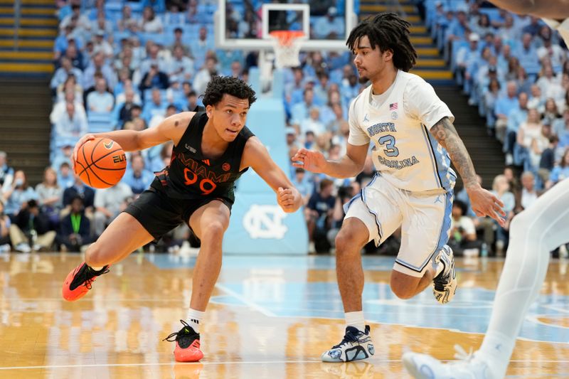Mar 1, 2025; Chapel Hill, North Carolina, USA;  Miami (Fl) Hurricanes guard Divine Ugochukwu (99) with the ball as North Carolina Tar Heels guard Elliot Cadeau (3) defends in the first half at Dean E. Smith Center. Mandatory Credit: Bob Donnan-Imagn Images