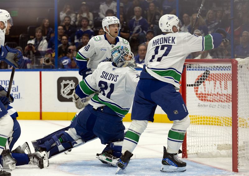 Oct 15, 2024; Tampa, Florida, USA; Vancouver Canucks goaltender Arturs Silovs (31) and defenseman Filip Hronek (17) defend the puck against the Tampa Bay Lightning during the first period at Amalie Arena. Mandatory Credit: Kim Klement Neitzel-Imagn Images