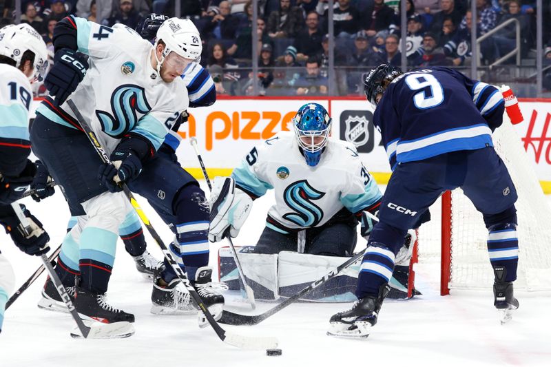 Mar 5, 2024; Winnipeg, Manitoba, CAN; Seattle Kraken defenseman Jamie Oleksiak (24) and Winnipeg Jets left wing Alex Iafallo (9) dig for a rebound in front of Seattle Kraken goaltender Joey Daccord (35) in the second period at Canada Life Centre. Mandatory Credit: James Carey Lauder-USA TODAY Sports