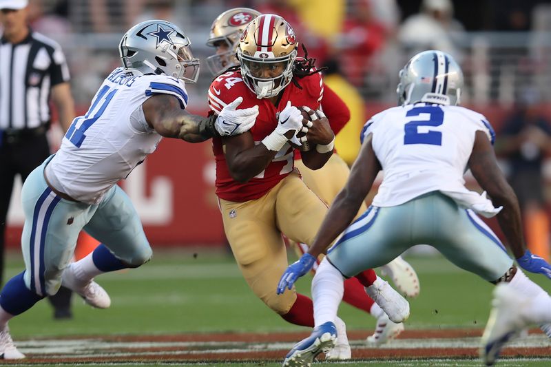 San Francisco 49ers running back Jordan Mason (24) runs between Dallas Cowboys linebacker Micah Parsons, left, and cornerback Jourdan Lewis (2) during the first half of an NFL football game in Santa Clara, Calif., Sunday, Oct. 8, 2023. (AP Photo/Jed Jacobsohn)