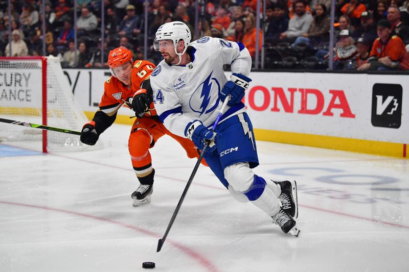 Dec 31, 2025; Anaheim, California, USA; Tampa Bay Lightning defenseman Max Crozier (24) moves the puck ahead of Anaheim Ducks center Mikael Granlund (64) during the second period at Honda Center. Mandatory Credit: Gary A. Vasquez-Imagn Images