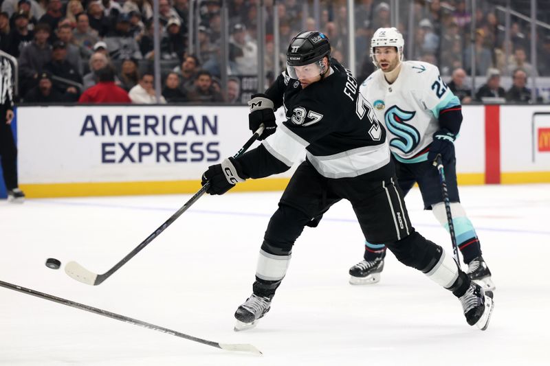 Nov 23, 2024; Los Angeles, California, USA;  Los Angeles Kings left wing Warren Foegele (37) shoots against Seattle Kraken right wing Oliver Bjorkstrand (22) during the second period at Crypto.com Arena. Mandatory Credit: Kiyoshi Mio-Imagn Images