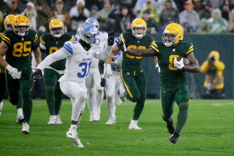 Green Bay Packers running back Josh Jacobs, right, runs past Detroit Lions safety Kerby Joseph (31) during the first half of an NFL football game Sunday, Nov. 3, 2024, in Green Bay, Wis. (AP Photo/Mike Roemer)