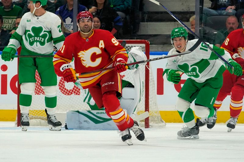 Mar 17, 2025; Toronto, Ontario, CAN; Calgary Flames forward Nazem Kadri (91) and Toronto Maple Leafs forward Mitch Marner (16) head up ice during the first period at Scotiabank Arena. Mandatory Credit: John E. Sokolowski-Imagn Images