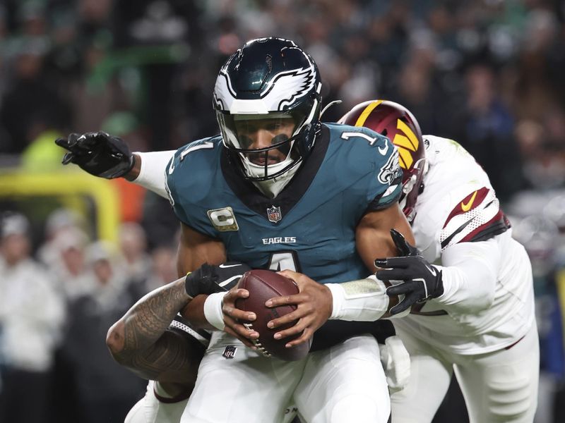 Philadelphia Eagles quarterback Jalen Hurts (1) gets sacked in the backfield during an NFL football game against the Washington Commanders, Thursday, Nov. 14, 2024, in Philadelphia, PA. (AP Photo/Peter Joneleit)