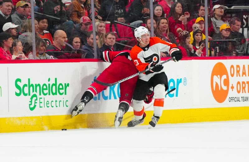 Mar 21, 2024; Raleigh, North Carolina, USA; Philadelphia Flyers right wing Bobby Brink (10) and Carolina Hurricanes defenseman Dmitry Orlov (7) battle over the puck during the second period at PNC Arena. Mandatory Credit: James Guillory-USA TODAY Sports