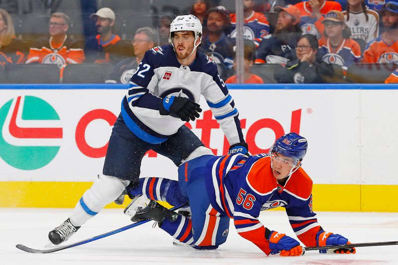 Sep 22, 2024; Edmonton, Alberta, CAN; Winnipeg Jets defensemen Dylan Coghlan (52) pulls down Edmonton Oilers forward William Nicholl (55) during the first period at Rogers Place. Mandatory Credit: Perry Nelson-Imagn Images