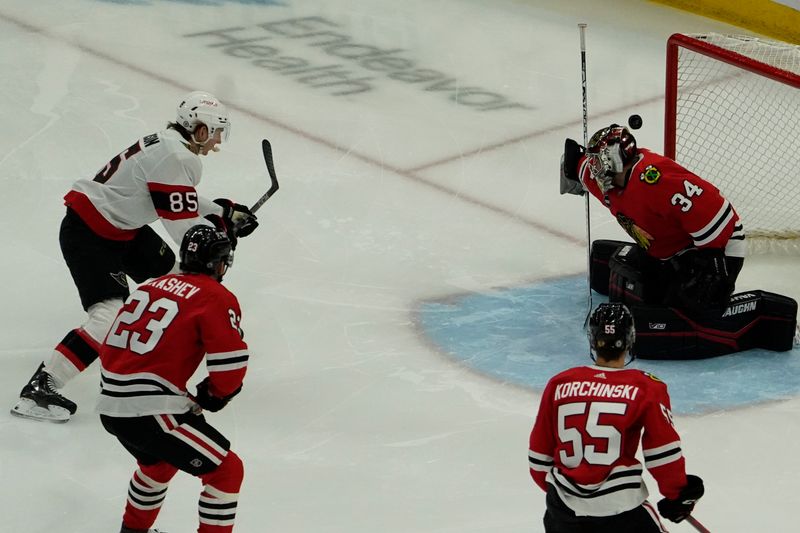 Feb 17, 2024; Chicago, Illinois, USA; Chicago Blackhawks goalie Petr Mrazek (34) makes a save on Ottawa Senators defenseman Jake Sanderson (85) during the first period at United Center. Mandatory Credit: David Banks-USA TODAY Sports