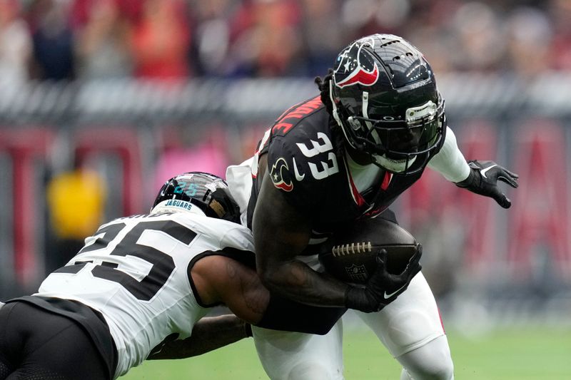 Houston Texans running back Dare Ogunbowale (33) tries to break a tackle by Jacksonville Jaguars cornerback Ronald Darby (25) after catching a pass during the second half of an NFL football game, Sunday, Sept. 29, 2024, in Houston. (AP Photo/Eric Gay)