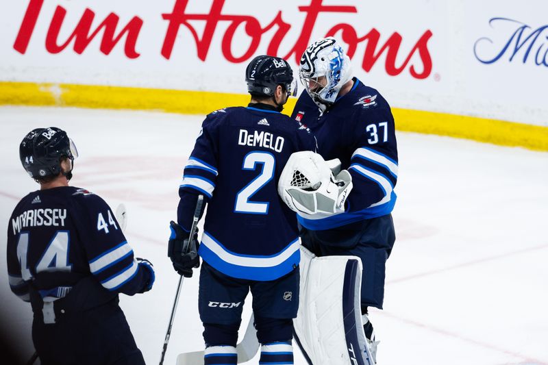 Apr 16, 2024; Winnipeg, Manitoba, CAN;  Winnipeg Jets goalie Connor Hellebuyck (37) is congratulated by Winnipeg Jets defenseman Dylan DeMelo (2) on a win against the Seattle Kraken at the end of the third period at Canada Life Centre. Mandatory Credit: Terrence Lee-USA TODAY Sports