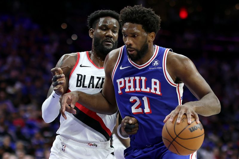 PHILADELPHIA, PENNSYLVANIA - OCTOBER 29: Joel Embiid #21 of the Philadelphia 76ers dribbles by Deandre Ayton #2 of the Portland Trail Blazers during the first quarter at Wells Fargo Center on October 29, 2023 in Philadelphia, Pennsylvania. NOTE TO USER: User expressly acknowledges and agrees that, by downloading and or using this photograph, User is consenting to the terms and conditions of the Getty Images License Agreement. (Photo by Tim Nwachukwu/Getty Images)