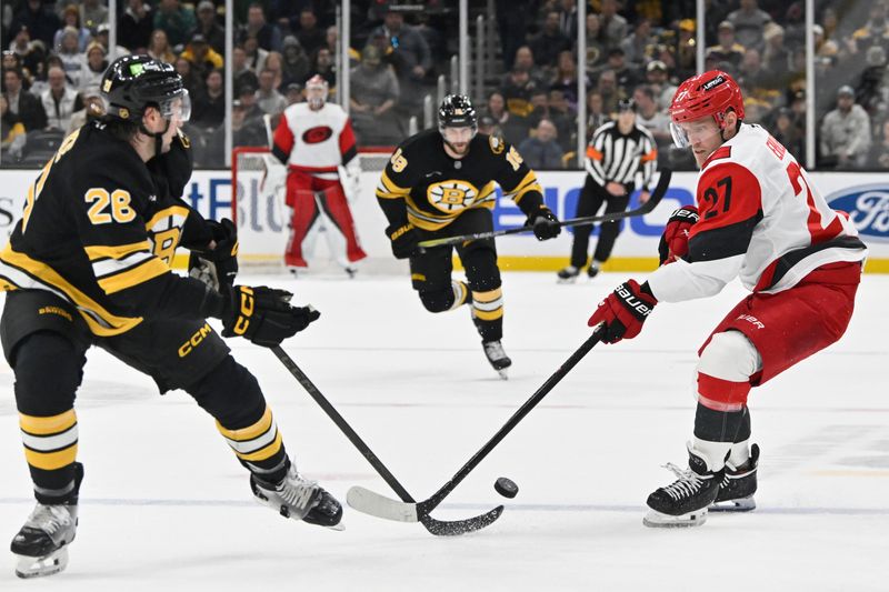 Nov 1, 2025; Boston, Massachusetts, USA; Carolina Hurricanes left wing Nikolaj Ehlers (27) plays the puck against Boston Bruins center Elias Lindholm (28) during the second period at TD Garden. Mandatory Credit: Eric Canha-Imagn Images