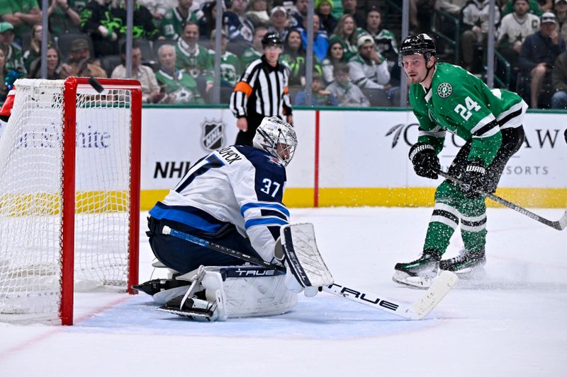 Apr 10, 2025; Dallas, Texas, USA; Dallas Stars center Roope Hintz (24) watches as the puck hits the crossbar behind Winnipeg Jets goaltender Connor Hellebuyck (37) during the second period at the American Airlines Center. Mandatory Credit: Jerome Miron-Imagn Images