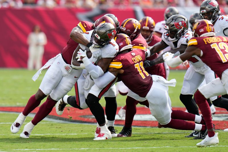 Tampa Bay Buccaneers running back Rachaad White, left, is stopped by the Washington Commanders defense including safety Jeremy Chinn (11) during the first half of an NFL football game Sunday, Sept. 8, 2024, in Tampa, Fla. (AP Photo/Chris O'Meara)