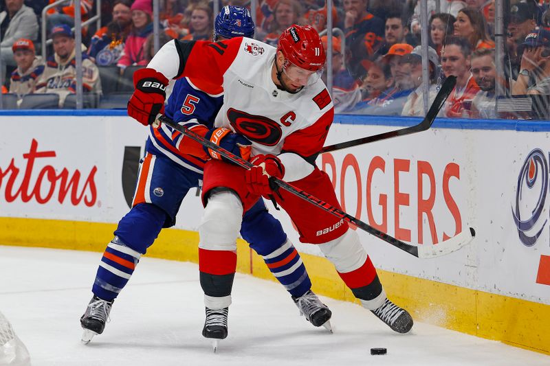 Mar 6, 2026; Edmonton, Alberta, CAN; Carolina Hurricanes forward Jordan Staal (11) and Edmonton Oilers defensemen Connor Murphy (5) battle for a loose puck during the second period at Rogers Place. Mandatory Credit: Perry Nelson-Imagn Images