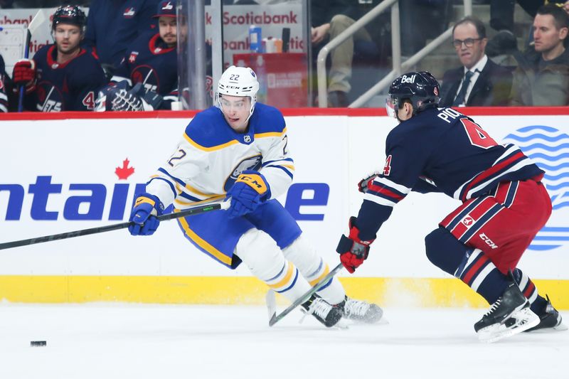 Jan 26, 2023; Winnipeg, Manitoba, CAN;  Buffalo Sabres forward Jack Quinn (22) tries to skate away from Winnipeg Jets defenseman Neal Pionk (4) during the first period at Canada Life Centre. Mandatory Credit: Terrence Lee-USA TODAY Sports