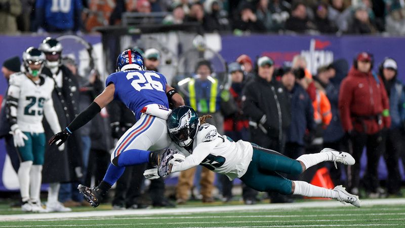 New York Giants running back Saquon Barkley (26) avoids a tackle by Philadelphia Eagles cornerback Bradley Roby (33) during the second quarter of an NFL football game, Sunday, Jan. 7, 2024, in East Rutherford, N.J. (AP Photo/Adam Hunger)