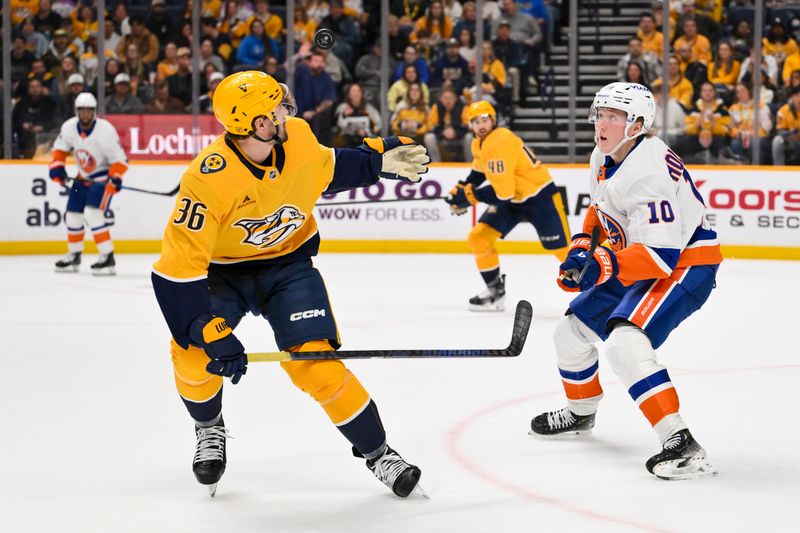 Jan 8, 2026; Nashville, Tennessee, USA; New York Islanders right wing Simon Holmstrom (10) and Nashville Predators left wing Cole Smith (36) battle for the puck during the second period at Bridgestone Arena. Mandatory Credit: Steve Roberts-Imagn Images