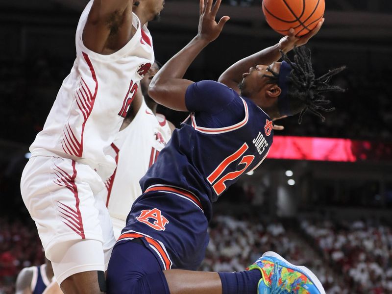 Jan 6, 2024; Fayetteville, Arkansas, USA; Auburn Tigers guard Denver Jones (12) shoots as Arkansas Razorbacks guard Truman Mark (12) defends during the first half at Bud Walton Arena. Mandatory Credit: Nelson Chenault-USA TODAY Sports