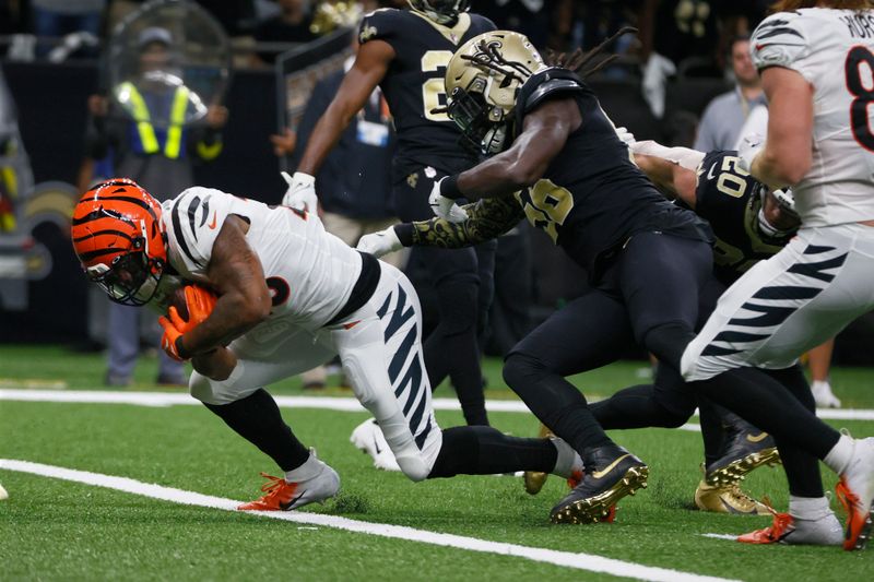 Cincinnati Bengals running back Joe Mixon, left, crosses the goal line for a touchdown past New Orleans Saints' Demario Davis (56) during the first half of an NFL football game in New Orleans, Sunday, Oct. 16, 2022. (AP Photo/Butch Dill)