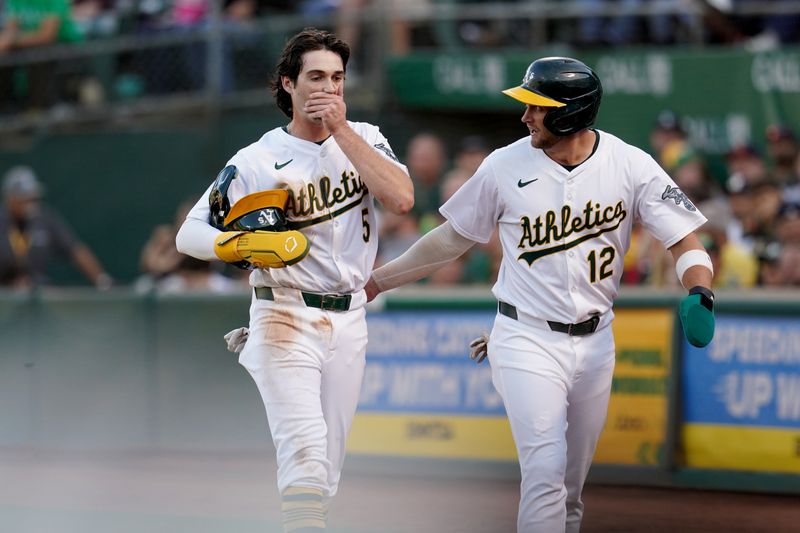 Jul 19, 2024; Oakland, California, USA; Oakland Athletics shortstop Jacob Wilson (5) reacts next to third baseman Max Schuemann (12) after suffering an injury against the Los Angeles Angels in the third inning at Oakland-Alameda County Coliseum. Mandatory Credit: Cary Edmondson-USA TODAY Sports