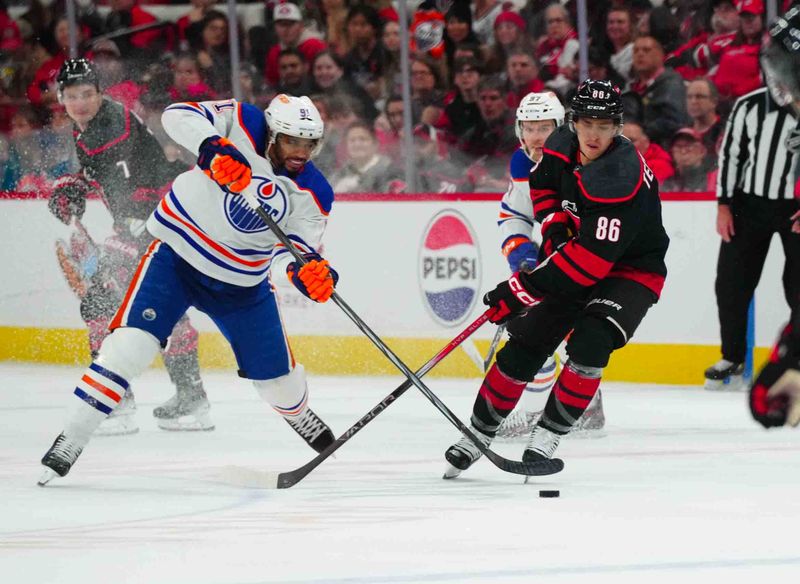 Nov 22, 2023; Raleigh, North Carolina, USA; Edmonton Oilers left wing Evander Kane (91) and Carolina Hurricanes left wing Teuvo Teravainen (86) go after the puck during the first period at PNC Arena. Mandatory Credit: James Guillory-USA TODAY Sports