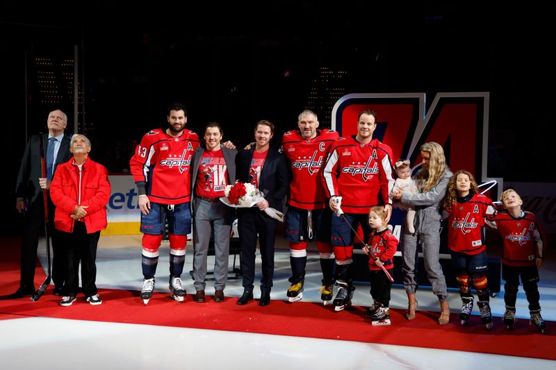 Apr 7, 2024; Washington, District of Columbia, USA; Washington Capitals defenseman John Carlson (74) poses for a picture with his family and Capitals teammates (L-R) right wing Tom Wilson (43), right wing T.J. Oshie, center Nicklas Backstrom, and left wing Alex Ovechkin (8) at a ceremony honoring his 1,000th NHL game prior to the game against the Ottawa Senators at Capital One Arena. Mandatory Credit: Geoff Burke-USA TODAY Sports