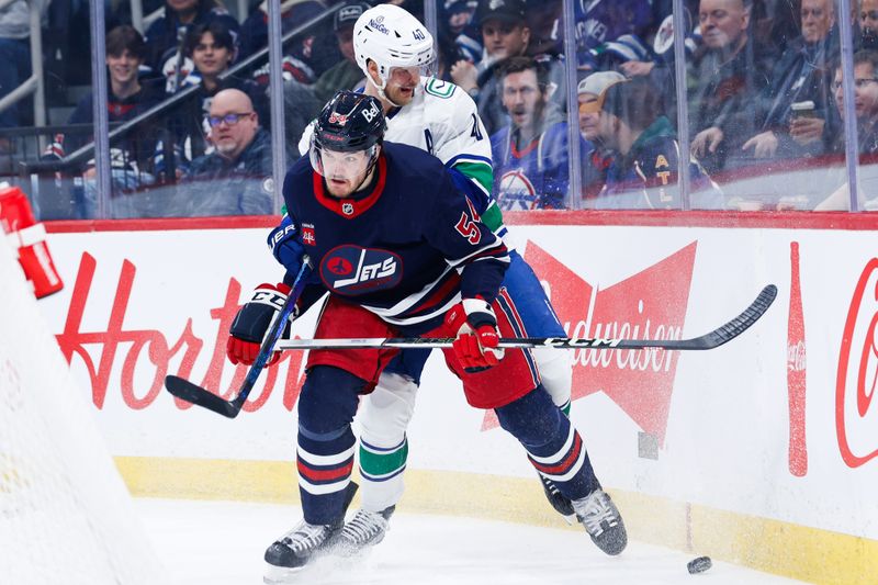 Jan 14, 2025; Winnipeg, Manitoba, CAN;  Winnipeg Jets defenseman Dylan Samberg (54) battles Vancouver Canucks forward Elias Pettersson (40) for the puck during the first period at Canada Life Centre. Mandatory Credit: Terrence Lee-Imagn Images