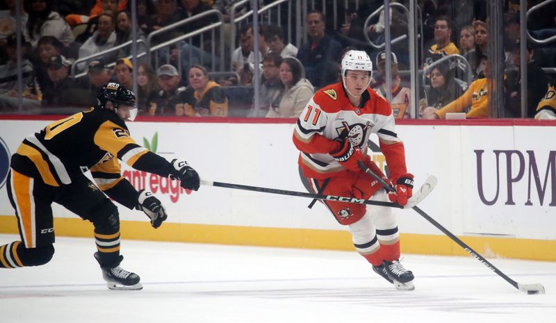 Oct 31, 2024; Pittsburgh, Pennsylvania, USA;  Anaheim Ducks center Trevor Zegras (11) moves the puck as Pittsburgh Penguins center Lars Eller (20) chases during the second period at PPG Paints Arena. Mandatory Credit: Charles LeClaire-Imagn Images