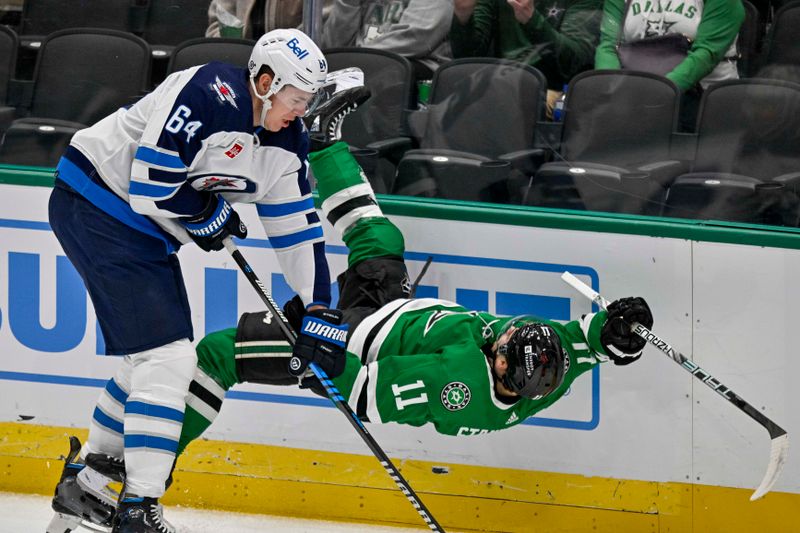 Apr 11, 2024; Dallas, Texas, USA; Winnipeg Jets defenseman Logan Stanley (64) checks Dallas Stars center Logan Stankoven (11) during the first period at the American Airlines Center. Mandatory Credit: Jerome Miron-USA TODAY Sports