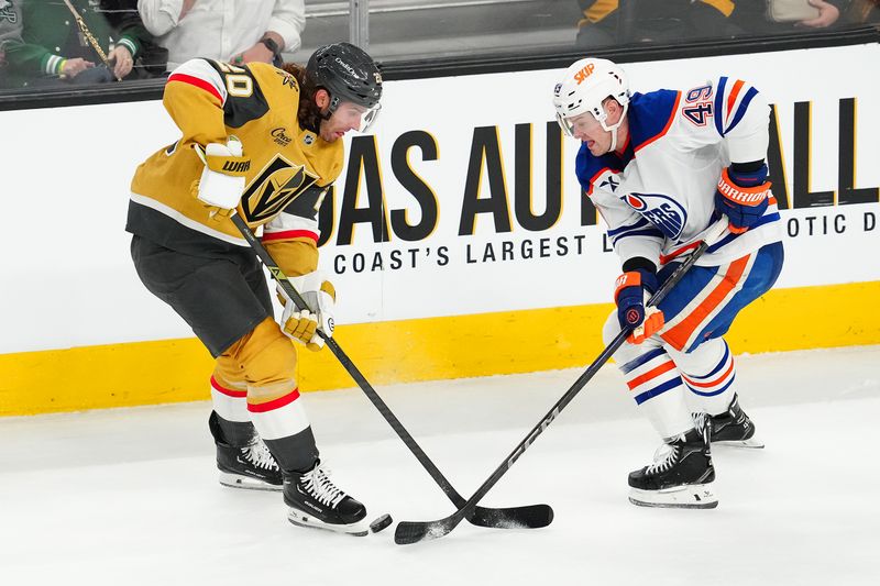 Apr 1, 2025; Las Vegas, Nevada, USA; Edmonton Oilers defenseman Ty Emberson (49) tips the puck away from Vegas Golden Knights left wing Brandon Saad (20) during the third period at T-Mobile Arena. Mandatory Credit: Stephen R. Sylvanie-Imagn Images