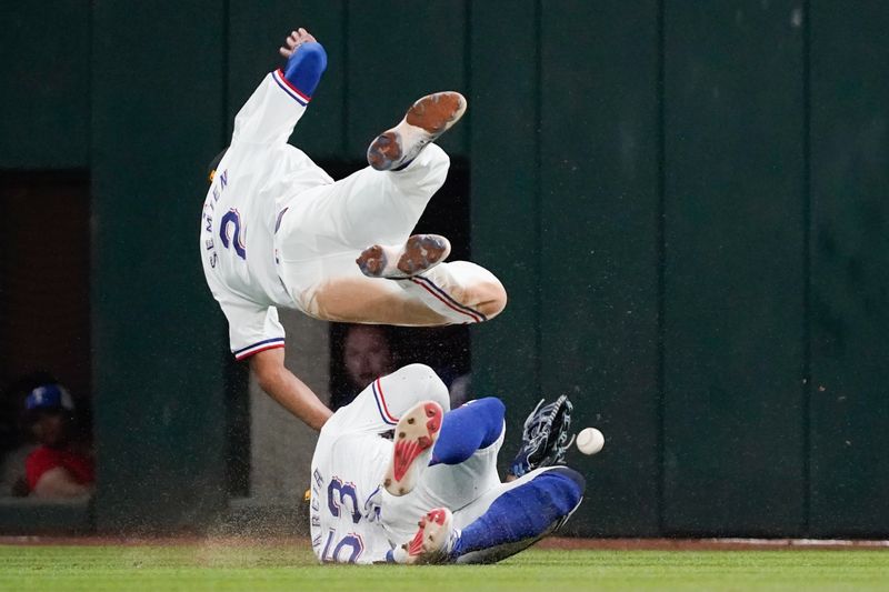 May 18, 2024; Arlington, Texas, USA; Texas Rangers second baseman Marcus Semien (2) collides with right fielder Adolis Garcia (53) chasing a fly ball during the sixth inning against the Los Angeles Angels at Globe Life Field. Mandatory Credit: Raymond Carlin III-USA TODAY Sports