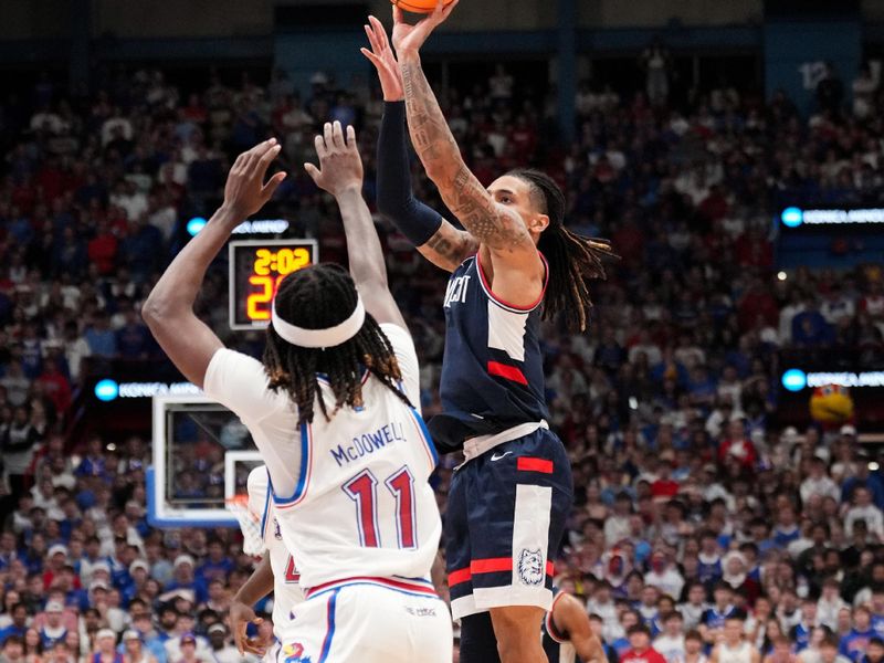 Dec 2, 2025; Lawrence, Kansas, USA; UConn Huskies guard Solo Ball (1) shoots over Kansas Jayhawks guard Jamari McDowell (11) during the first half of the game at Allen Fieldhouse. Mandatory Credit: Denny Medley-Imagn Images