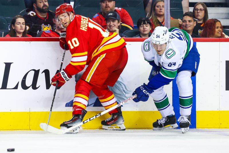 Sep 28, 2024; Calgary, Alberta, CAN; Calgary Flames center Jonathan Huberdeau (10) passes the puck against Vancouver Canucks center Aatu Raty (54) during the second period at Scotiabank Saddledome. Mandatory Credit: Sergei Belski-Imagn Images