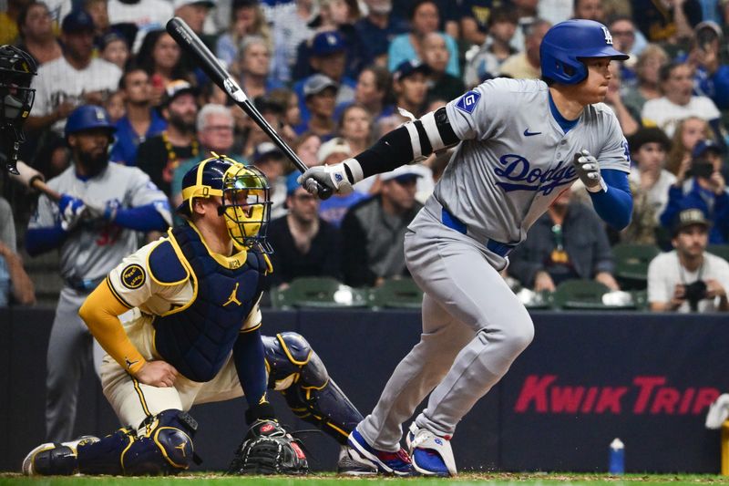 Aug 15, 2024; Milwaukee, Wisconsin, USA; Los Angeles Dodgers designated hitter Shohei Ohtani (17) hits a single as Milwaukee Brewers catcher William Contreras (24) looks on in the fifth inning at American Family Field. Mandatory Credit: Benny Sieu-USA TODAY Sports