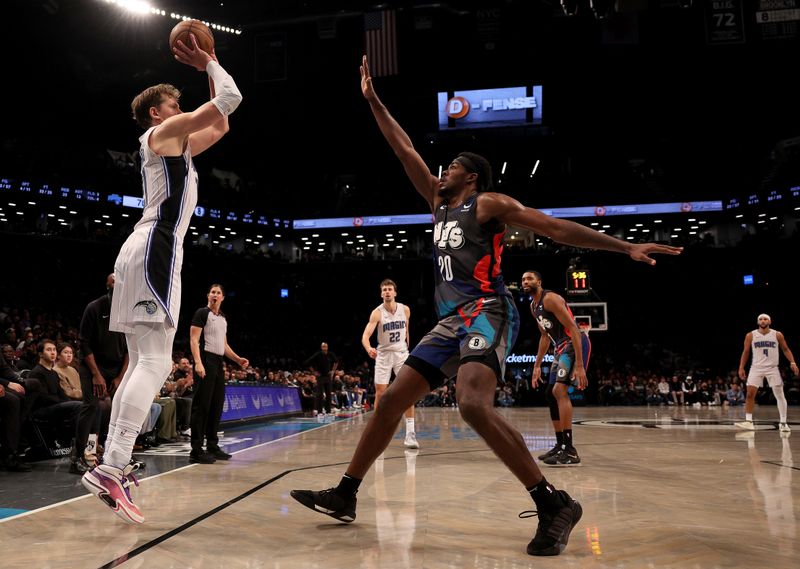 NEW YORK, NEW YORK - DECEMBER 02: Moritz Wagner #21 of the Orlando Magic shoots a three point shot as Day'Ron Sharpe #20 of the Brooklyn Nets defends during the second half at Barclays Center on December 02, 2023 in New York City. The Brooklyn Nets defeated the Orlando Magic 129-101. NOTE TO USER: User expressly acknowledges and agrees that, by downloading and or using this photograph, User is consenting to the terms and conditions of the Getty Images License Agreement. (Photo by Elsa/Getty Images)