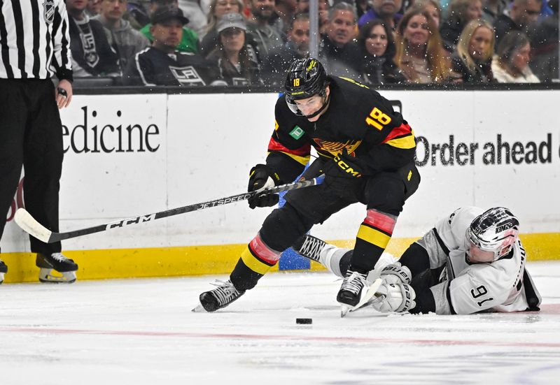 Apr 10, 2023; Los Angeles, California, USA;  Los Angeles Kings right wing Carl Grundstrom (91) reaches for the puck against Vancouver Canucks center Jack Studnicka (18) in the first period at Crypto.com Arena. Mandatory Credit: Jayne Kamin-Oncea-USA TODAY Sports