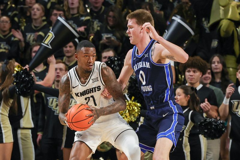 Jan 13, 2024; Orlando, Florida, USA; UCF Knights forward C.J. Walker (21) looks to pass against Brigham Young Cougars forward Noah Waterman (0) during the first period at Addition Financial Arena. Mandatory Credit: Mike Watters-USA TODAY Sports