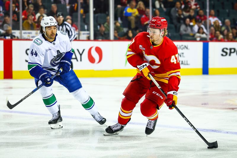 Oct 1, 2025; Calgary, Alberta, CAN; Calgary Flames center Connor Zary (47) controls the puck against Vancouver Canucks left wing Kiefer Sherwood (44) during the second period at Scotiabank Saddledome. Mandatory Credit: Sergei Belski-Imagn Images