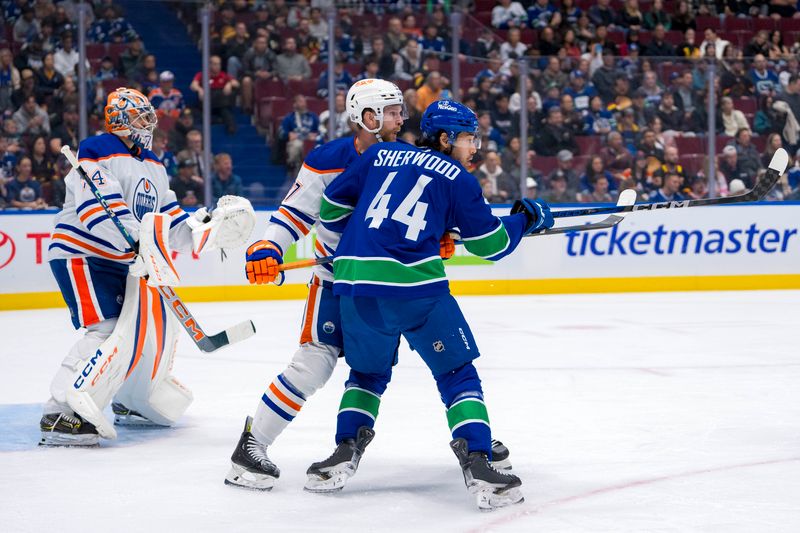 Oct 4, 2024; Vancouver, British Columbia, CAN; Edmonton Oilers goalie Stuart Skinner (74) watches as defenseman Brett Kulak (27) battles with Vancouver Canucks forward Kiefer Sherwood (44) during the first period at Rogers Arena. Mandatory Credit: Bob Frid-Imagn Images