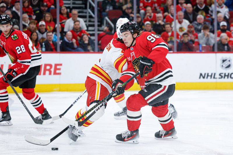 Jan 15, 2026; Chicago, Illinois, USA; Calgary Flames defenseman Rasmus Andersson (4) defends against Chicago Blackhawks center Connor Bedard (98) during the first period at United Center. Mandatory Credit: Kamil Krzaczynski-Imagn Images