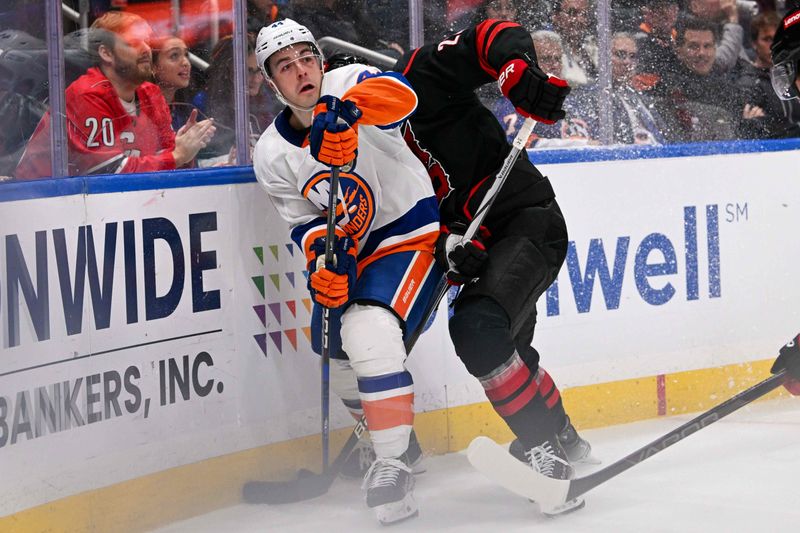 Mar 19, 2024; Elmont, New York, USA; New York Islanders center Jean-Gabriel Pageau (44) and Carolina Hurricanes defenseman Brett Pesce (22) battle for the puck along the boards during the second period at UBS Arena. Mandatory Credit: Dennis Schneidler-USA TODAY Sports