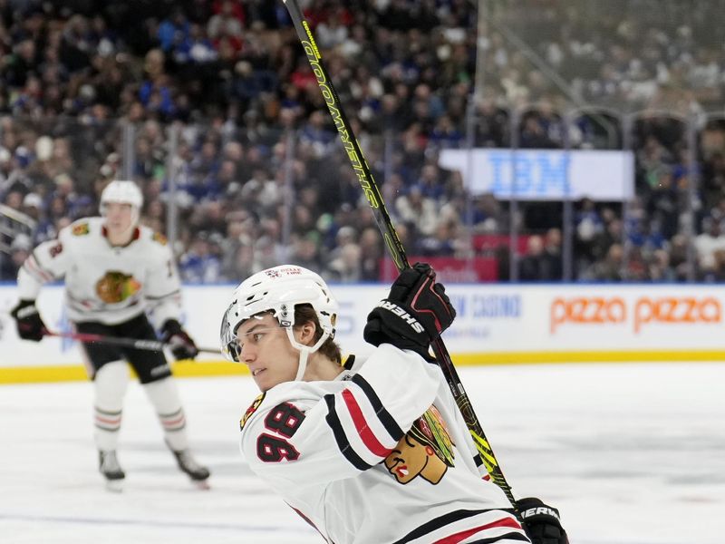 Dec 2, 2024; Toronto, Ontario, CAN; Chicago Blackhawks forward Connor Bedard (98) shoots the puck against the Toronto Maple Leafs during the second period at Scotiabank Arena. Mandatory Credit: John E. Sokolowski-Imagn Images