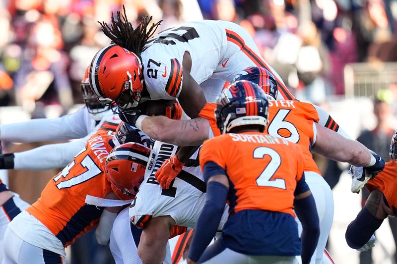 Cleveland Browns running back Kareem Hunt (27) leaps for a first down as Denver Broncos linebacker Josey Jewell (47) and cornerback Pat Surtain II (2) defend during the first half of an NFL football game on Sunday, Nov. 26, 2023, in Denver. (AP Photo/Jack Dempsey)