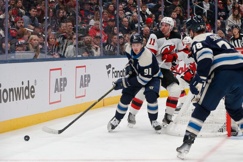 Dec 31, 2025; Columbus, Ohio, USA; Columbus Blue Jackets center Kent Johnson (91) passes the puck as New Jersey Devils left wing Stefan Noesen (11) trails the play during the first period at Nationwide Arena. Mandatory Credit: Russell LaBounty-Imagn Images