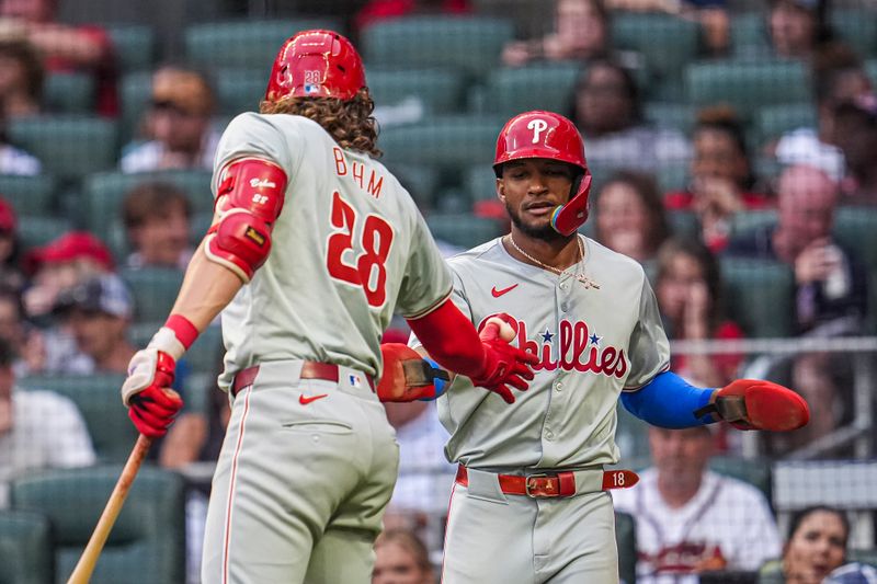 Jul 6, 2024; Cumberland, Georgia, USA; Philadelphia Phillies outfielder Johan Rojas (18) shakes hands with third baseman Alec Bohm (28) after scoring a run against the Atlanta Braves during the third inning at Truist Park. Mandatory Credit: Dale Zanine-USA TODAY Sports