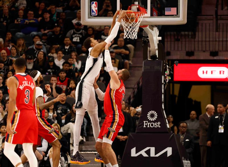 SAN ANTONIO, TX - DECEMBER 17:  Victor Wembanyama #1 of the San Antonio Spurs dunks over Jonas Valanciunas #17 of the New Orleans Pelicans in the first half at Frost Bank Center on December  17, 2023 in San Antonio, Texas. NOTE TO USER: User expressly acknowledges and agrees that, by downloading and or using this photograph, User is consenting to terms and conditions of the Getty Images License Agreement. (Photo by Ronald Cortes/Getty Images)