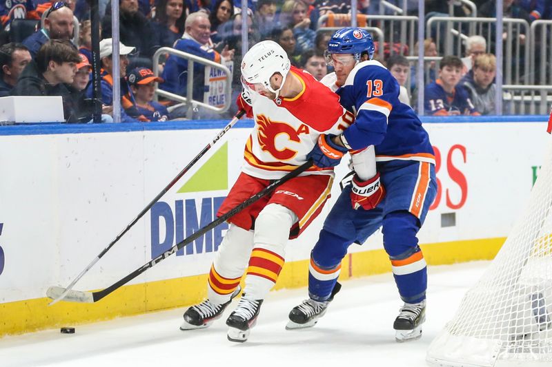 Feb 10, 2024; Elmont, New York, USA;  New York Islanders center Mathew Barzal (13) and Calgary Flames center Jonathan Huberdeau (10) battle for control of the puck in the first period at UBS Arena. Mandatory Credit: Wendell Cruz-USA TODAY Sports